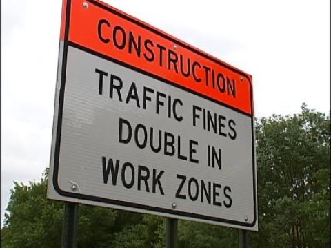 A roadside sign reading CONSTRUCTION, TRAFFIC FINES DOUBLE IN WORK ZONES.