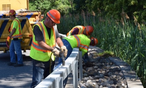 A road crew in high-visibility gear working beside an open travel lane.